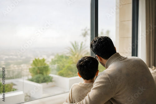 Father and son behind the balcony window of the house