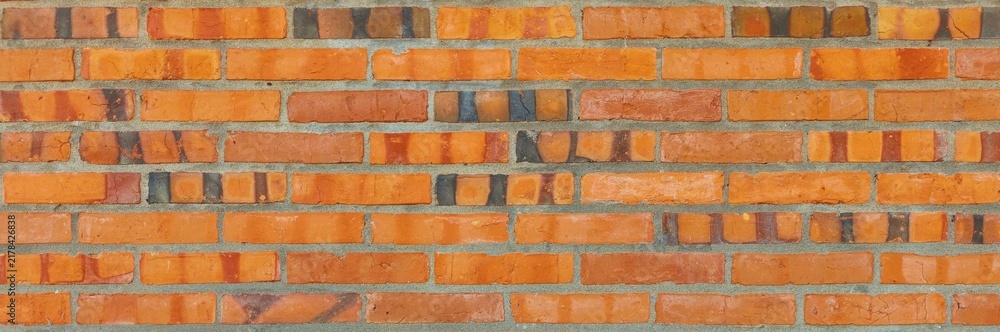 Fototapeta premium Orange brick wall constructing a textured background with varying earthy tones