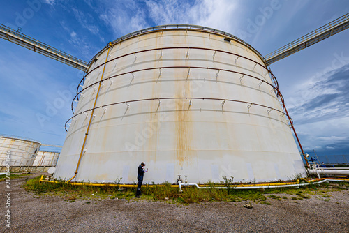 Asian male industrial engineers use a top roof visual tank view of the new installation and crude oil