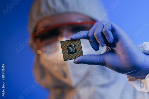 Laboratory technician holding microchip in cleanroom environment, concept control quality of semiconductor on lab of artificial intelligence factory