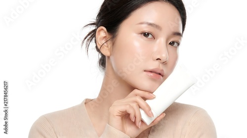 Beautiful young Asian woman holding a blank white cosmetic product container for branding.