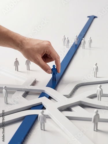 Hand places blue figure on arrow path among white figurines representing team selection and career guidance on white background with standing white surface arrow pathway with hand selects