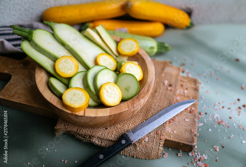 Cutting green and yellow  zucchini in a wooden bowl 
