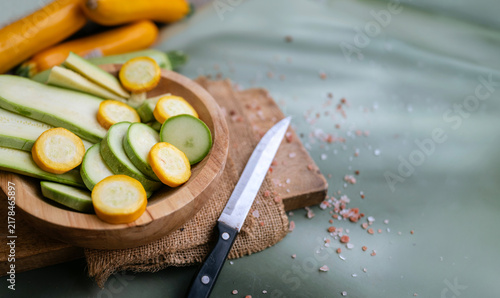 Cutting green and yellow  zucchini in a wooden bowl 