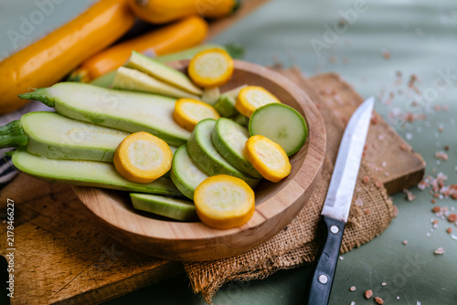 Cutting green and yellow  zucchini in a wooden bowl 
