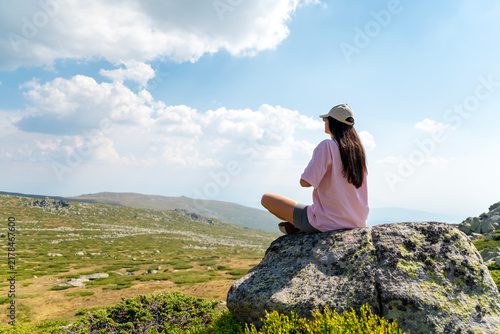 Relaxed woman meditating and  breathing fresh air in the summer mountain	