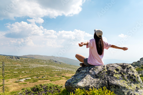Relaxed woman meditating and  breathing fresh air in the summer mountain	
