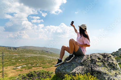 Beautiful Woman taking selfie pictures with her phone in the mountain 