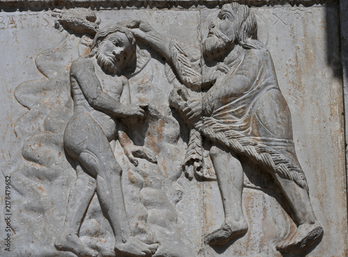Medieval stone relief depicting the baptism of Jesus by Saint John the Baptist in Verona, Italy