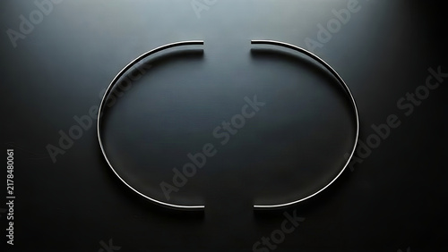 Two polished metal half-circles forming a complete circle on dark surface.