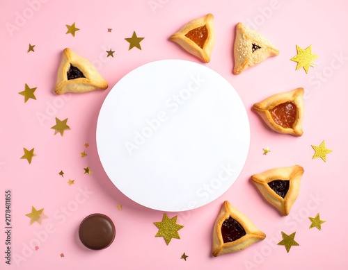 Hamantaschen cookies, stars, chocolate, circle, and confetti arranged on a pink surface