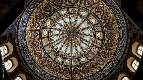 Intricate geometric tilework inside a mosque dome in gold and blue.