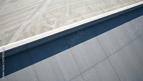 Geometric concrete slope casting sharp shadows in minimalist industrial setting.