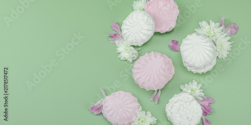 Fruit marshmallow with fresh flower petals on pastel green background. Lactose free vegan dessert