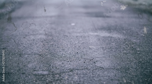 Grainy grey pavement texture with vintage film marks and shallow depth of field on an empty urban street