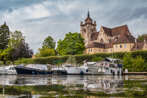 Fotografie Bateaux de plaisance amarrés sur le canal à Dole, collégiale Notre-Dame en arriè