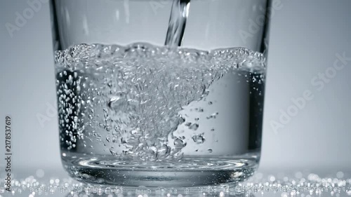 Clear water pouring into a transparent glass creating bubbles and splashes on a white background with video clear refreshment refreshing hydration drinking aeration with lighting