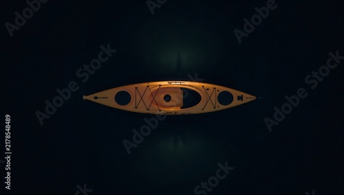 Single yellow kayak floating on dark calm water viewed from a high angle aerial perspective