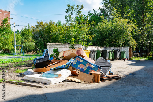 A pile of old furniture discarded near the trash cans in the courtyard.