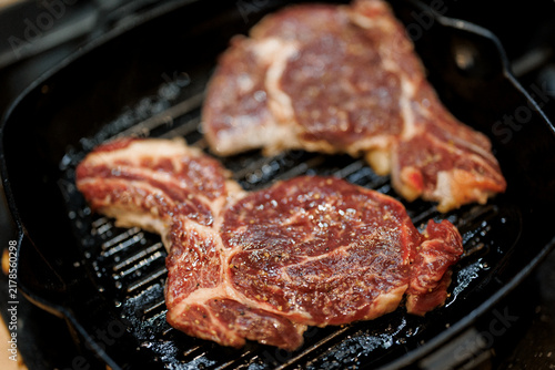 Grilled steak sizzle on cast iron grill with bold marbling and salt pepper seasoning for hungry home cook meal