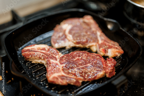 Two thick steaks sizzle on a hot grill pan as they cook for a delicious meal ready to be enjoyed