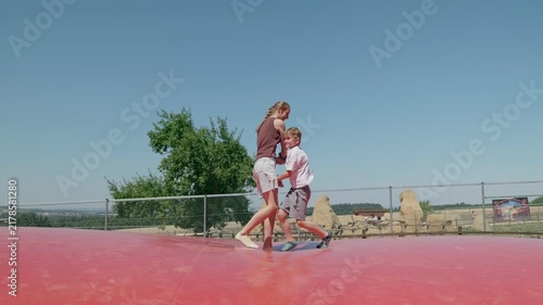 A brother and sister are dancing and jumping on a trampoline slow motion