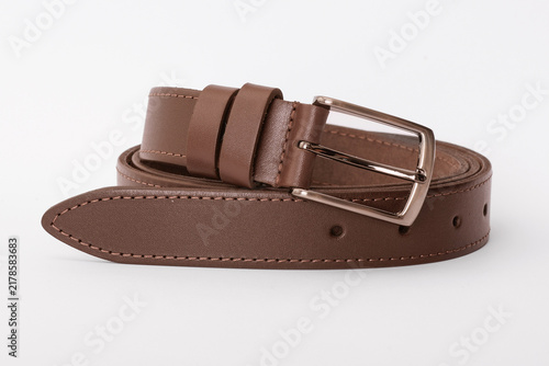 Brown stitched leather belt coiled with a rectangular metal buckle isolated on a white background