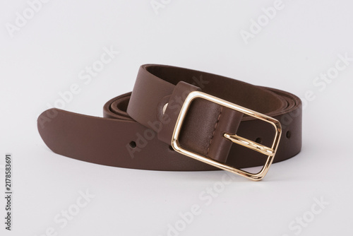 Dark brown smooth leather belt coiled with a rectangular gold metal buckle on a white background