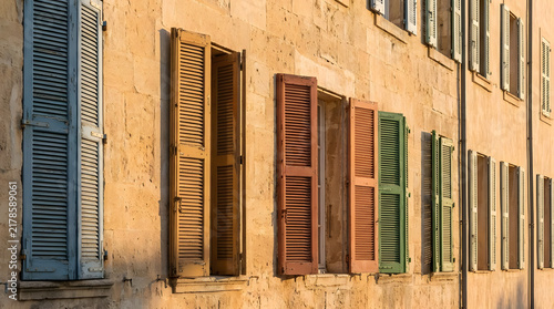 Colorful wooden window shutters on old stone building facade.