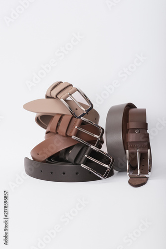 Stack of colorful leather belts with metal buckles isolated on a white background