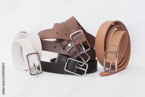 Set of white, brown, beige and black leather belts with silver buckles on a white background
