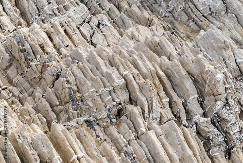 Natural rock formation characterized by distinct inclined sedimentary layers, revealing the geological structure