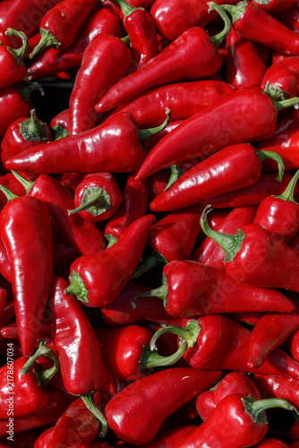 Foto Fresh ripe red hot chili peppers and raw Capsicum annuum harvested for spicy culinary ingredients at an outdoor street market display in natural daylight, vertical shot, Warsaw, Poland