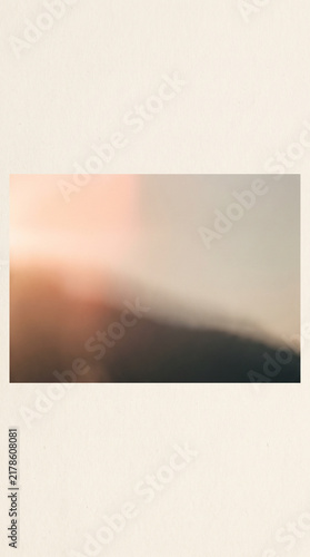 Abstract soft focus background featuring a warm golden hour light gradient blending into dark shadows on a textured paper frame for minimalist artistic design and commercial projects