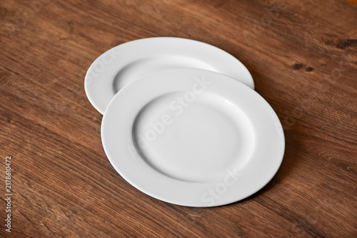 Ceramic white flat plate for food on wooden table top view