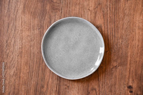 Ceramic white flat plate for food on wooden table top view