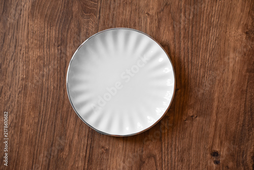 Ceramic white flat plate for food on wooden table top view
