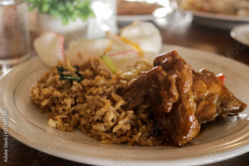 Plate of Savory Rice and Glazed Chicken Served on Beige Dish in Cozy Restaurant Setting