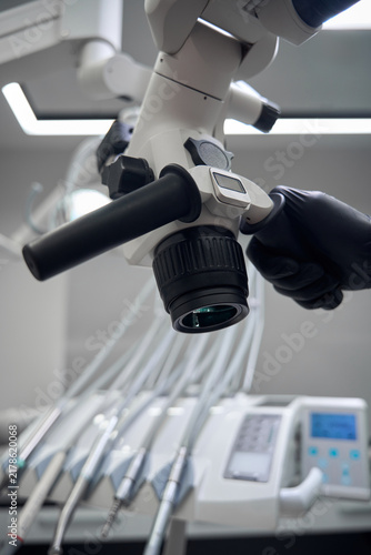 Person adjusting microscope in medical clinic during daytime