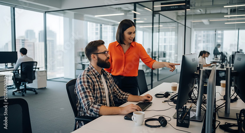 Female supervisor pointing at computer screen while giving feedback to male colleague