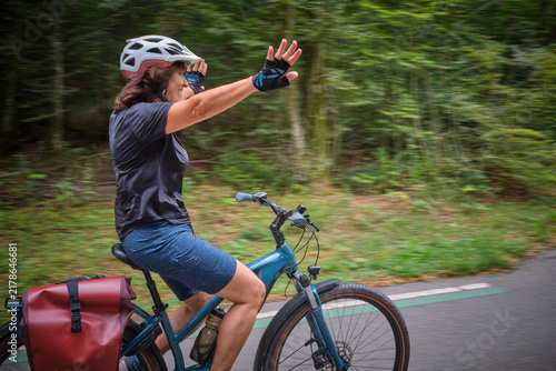 Obraz na płótnie active senior woman having fun practicing handsfree cycling on a bike path through a peaceful forest, showing balance, confidence, freedom and active aging