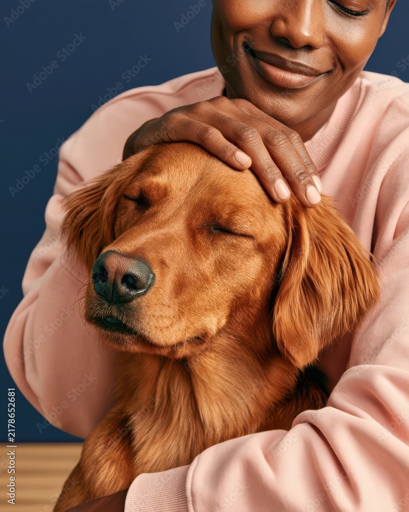 Obraz premium Smiling person gently pets a content golden retriever in a close-up portrait showing affection and bond