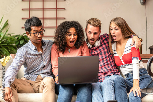 Foto Multiethnic gen z friends react with surprise while watching unexpected content together on a laptop