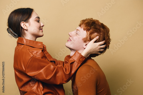 Quadro su tela Couple, woman and man with love and affection in warm clothing on brown background