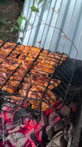 Grilled pork steaks cooking on barbecue grill grate over glowing charcoal embers. Outdoor barbecue process, juicy marinated meat grilling close up, summer picnic and street food concept.