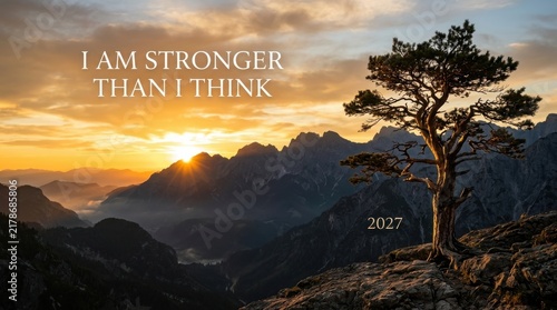 Inspirational sunset mountain landscape with motivational quote, lone tree on rocky peak at sunrise, 2027 vision concept