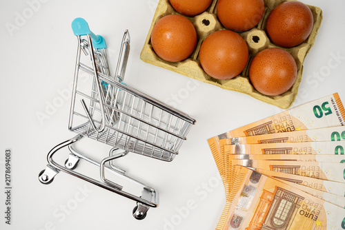 Photography Mini shopping cart, eggs, and 50 Euro banknotes representing inflation, high foo