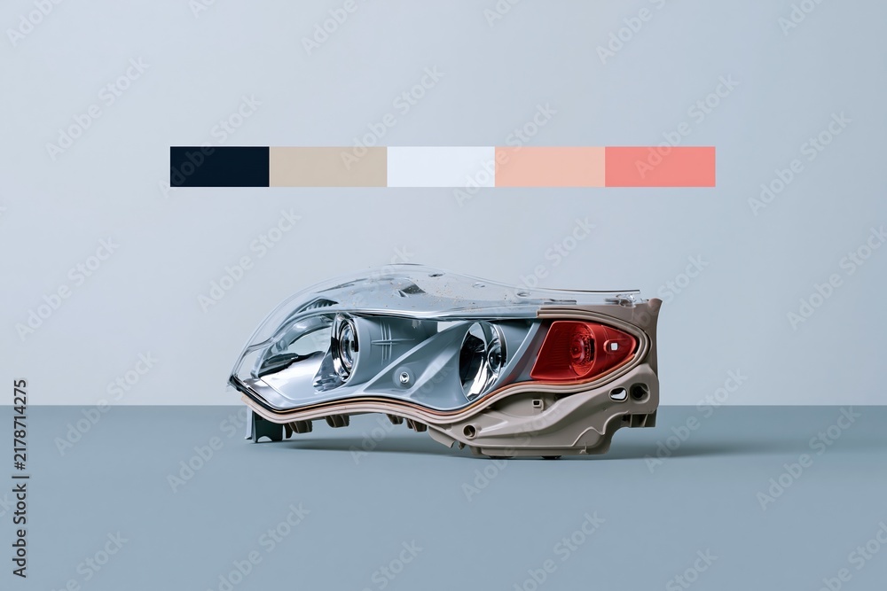 Fototapeta premium Modern automotive headlamp assembly with a polished polycarbonate cover and red signal, isolated on a grey surface for a vehicle repair catalog