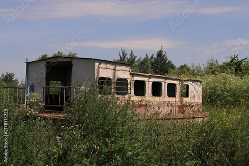 Foto An old metal river boat with traces of rust and peeling paint standing in tall grass under a clear summer sky