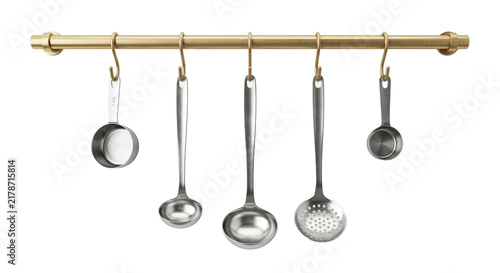 Kitchen utensil set includes ladles and measuring cups hanging from golden rail for organized culinary tools.